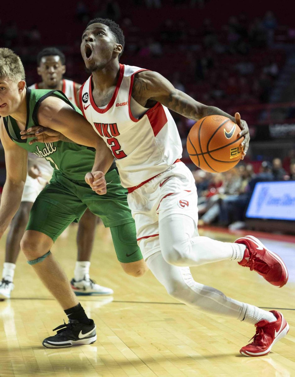 WKU guard Don McHenry (2) makes a face as he pushes against Marshall’s defense in an attempt to drive toward the basket during the basketball game in E.A. Diddle Arena on Saturday, Nov. 30, 2024. 