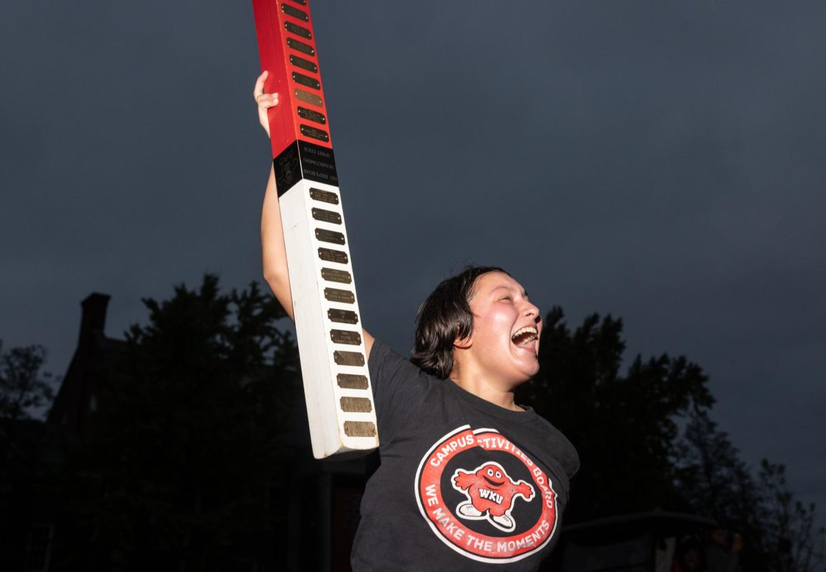 Senior Coordinator for the Campus Activities Board Elliot Bollinger hoists the spirit stick before the WKU Homecoming Parade in Bowling Green on Friday, Nov. 15, 2024. 