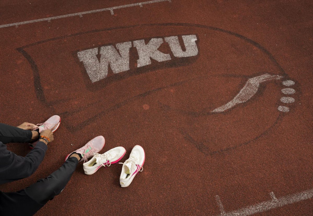 Junior Garrett Steed laces up his spikes in between sets of a workout on Western Kentucky University's track in Bowling Green, Ky.