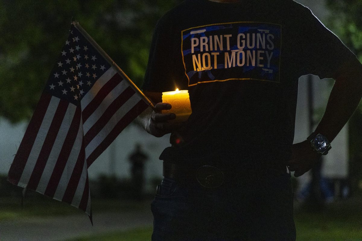 Ben Leneave holds a candle and American flag during the WKU chapter of Turning Point USA’s vigil for conservative commentator Charlie Kirk on the South Lawn on Thursday, Sept. 25, 2025.
