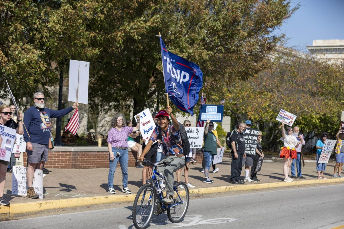 Gabriel Chamber waves pro Trump flag as he rides down on his bike as the sole counter protester at SOKY Indivisible No Kings protest on October 18, 2025.