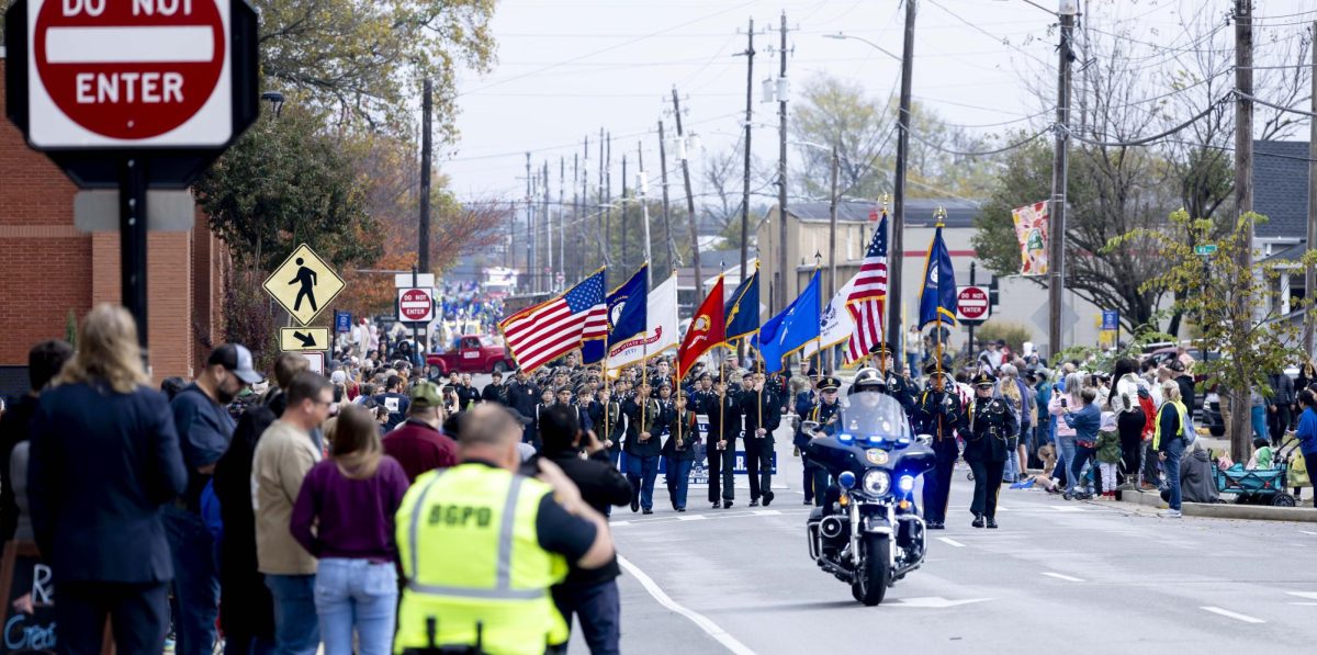 Bowling Green residents stand on the edge of State Street while JROTC cadets, local military, elected officials, and other parade participants march downtown on Saturday, Nov. 8, 2025 during Bowling Green’s Veteran’s Day Parade. 
