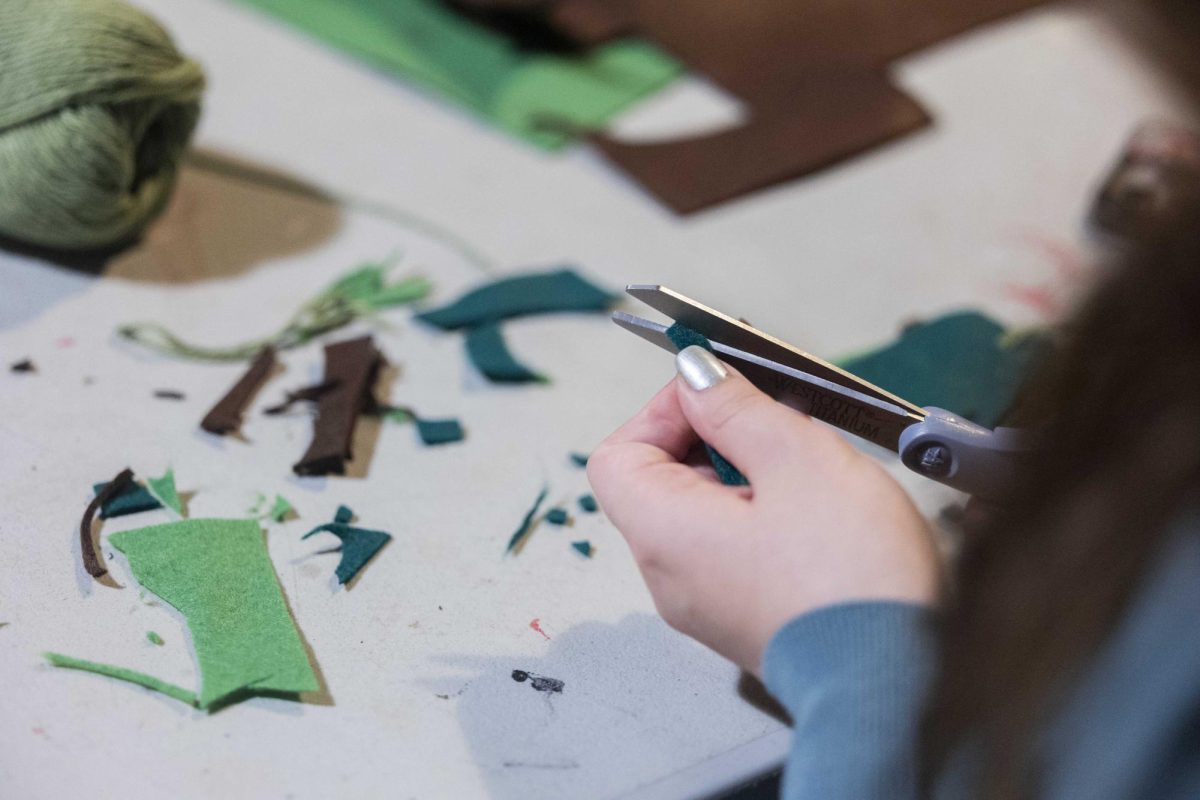 Ellie Ralston, a senior architecture major, cuts small pieces of greens to add to her plant ornament during WKU’s Horticulture Club DIY Ornament night at the greenhouse on Monday, Nov. 24, 2025. 