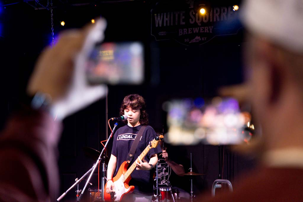 A concert attendee films Bowling Green Rock Band Academy House Band’s performance at White Squill Brewery on Saturday, Nov. 22, 2025 as the first act of the night for Pints for Public Media.