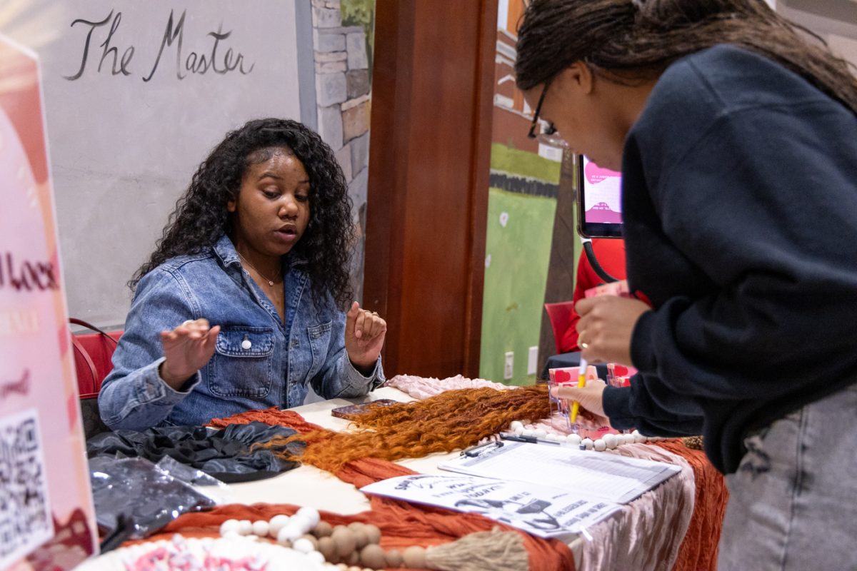 Junior interior design major Kyla Bryant speaks with passersby about her hairstyling business Blessed Locs on the first floor of Downing Student Union during the Black Student Alliance’s Black Excellence after Dark on Tuesday, Feb. 3, 2026.