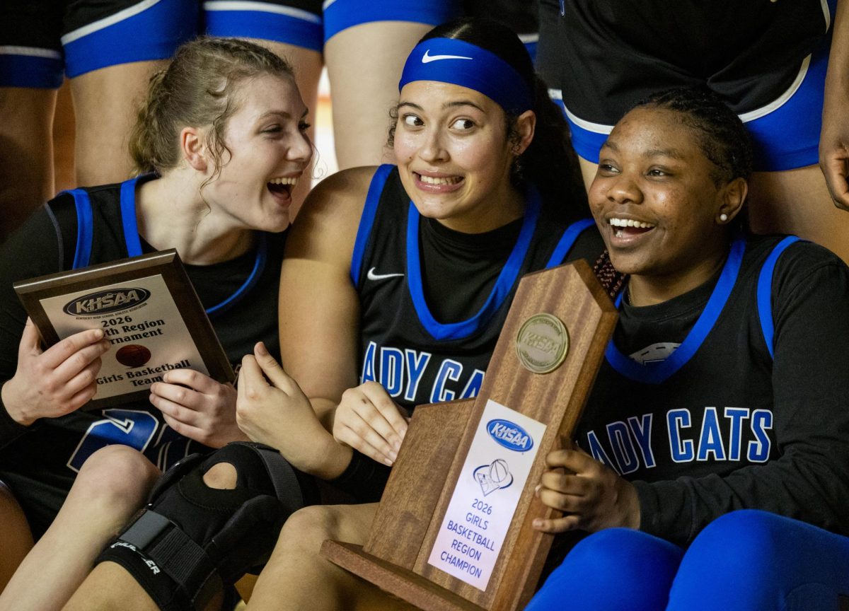 Franklin-Simpson High School seniors Reece Mylor (20), Kloie Smith (15) and Tiffany Harrigan (5) gather around the KHSAA 2026 Fourth Region championship trophy after their 60-56 win over Barren County High School during the KHSAA Fourth Region girls basketball championship game at E.A. Diddle Arena on Saturday, March 7, 2026. 