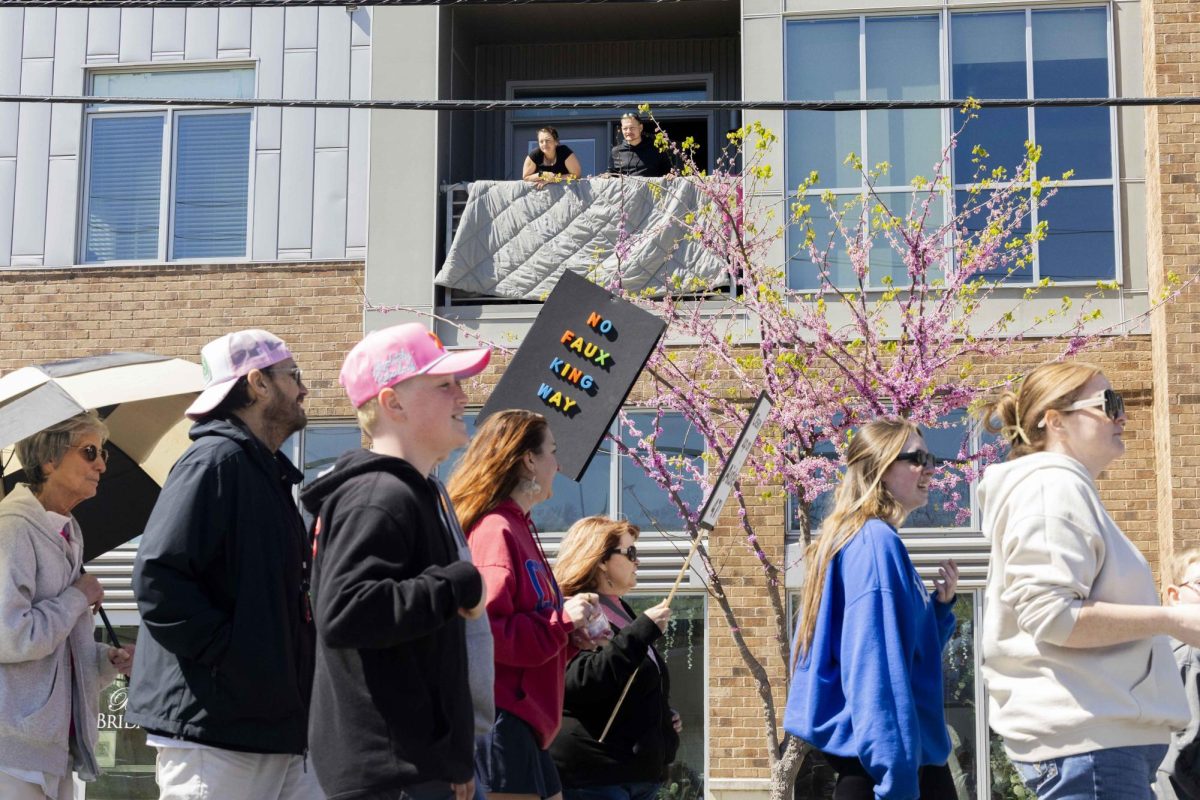 Residents watch from their homes as protestors move through the streets during the No King's protest in Bowling Green, Kentucky on Saturday, March 28, 2026.