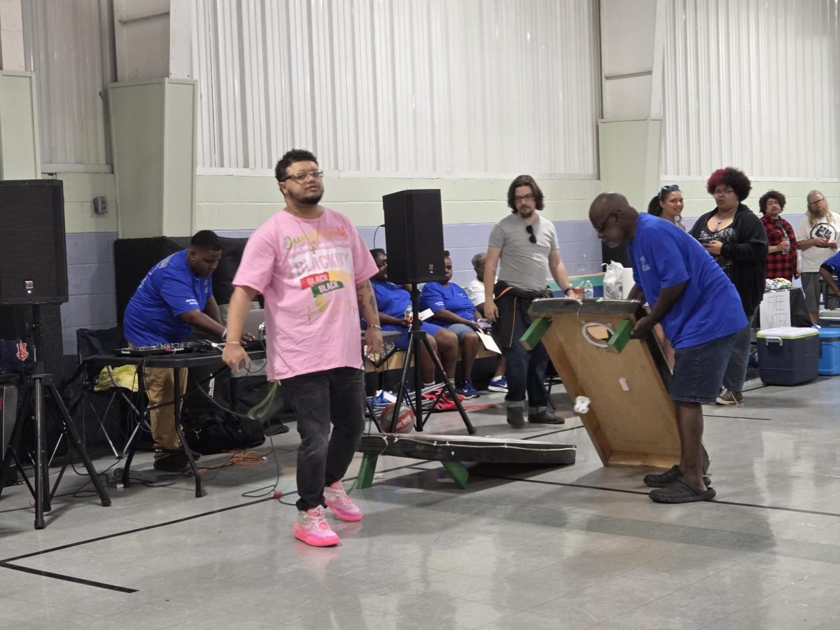 Local artist King Adam prepares to take the stage during the BG Freedom Walkers Juneteenth event as members lay down cornhole tables. Photo taken in the Foundry Christian Community Center on June 20. 
