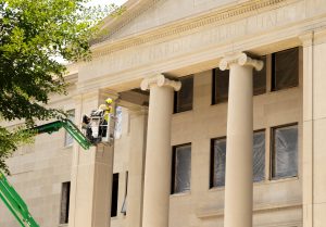 A construction worker is lowered to the ground after working on renovating the front exterior of Henry Hardin Cherry Hall on July 7, 2026.